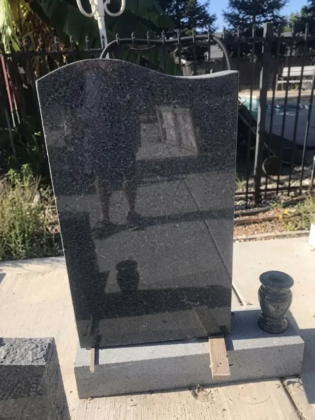 Polished black granite headstone with a serpentine top on a grey granite base