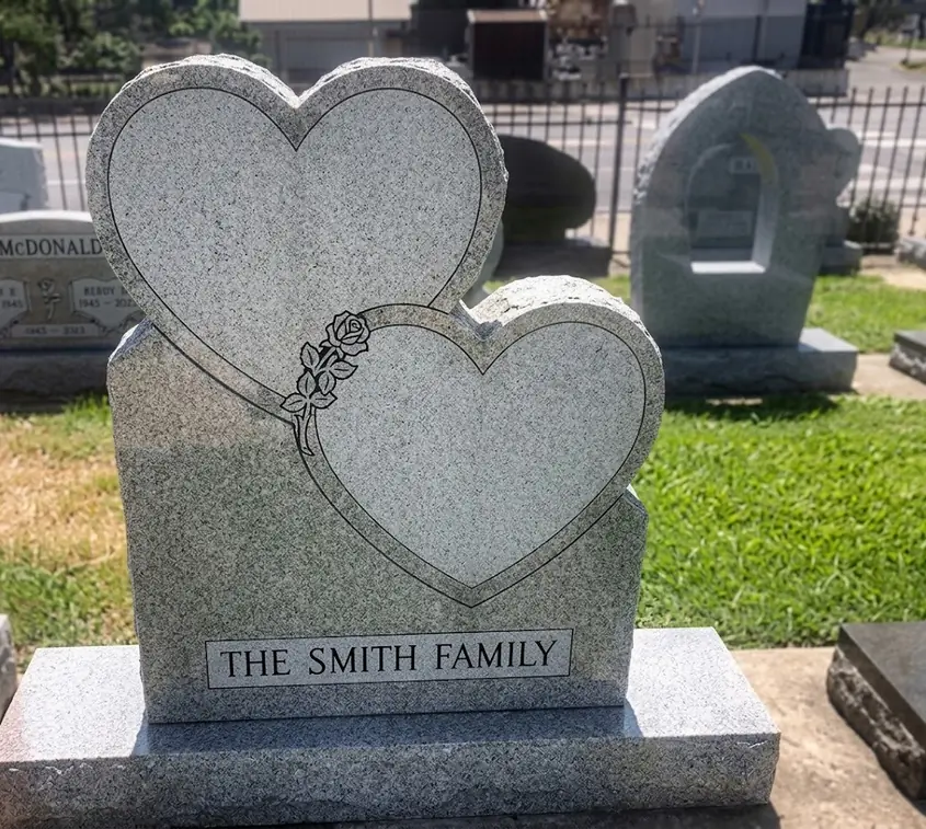 Grey granite companion monument shaped as two joined hearts with an etched rose